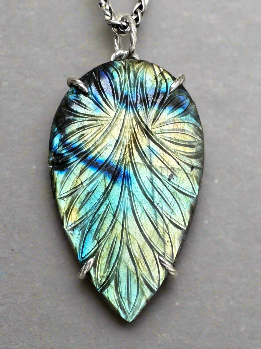 Multicolored leaf-shaped pendant on a textured fabric background